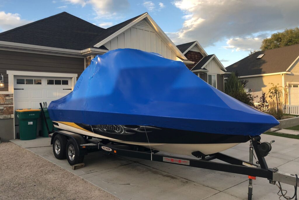 A boat shrink wrapped in a driveway